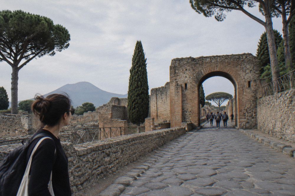 Sunlit colonnaded ruin inside Pompeii with worn marble steps and fragmentary walls