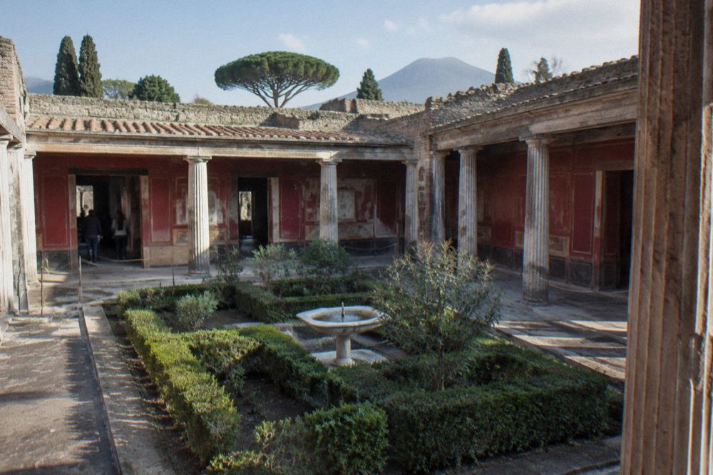 Volcanic stone walls and an excavated street at Pompeii under an open sky