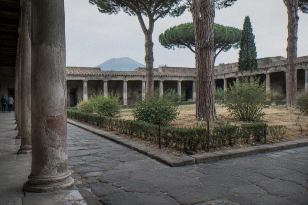 Straight ancient street of stone paving running between ruined walls at Pompeii