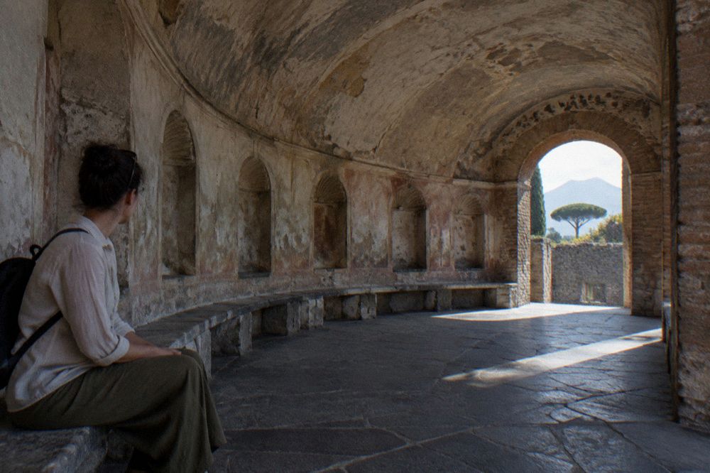 Crowds of visitors walking along a wide ancient street inside Pompeii
