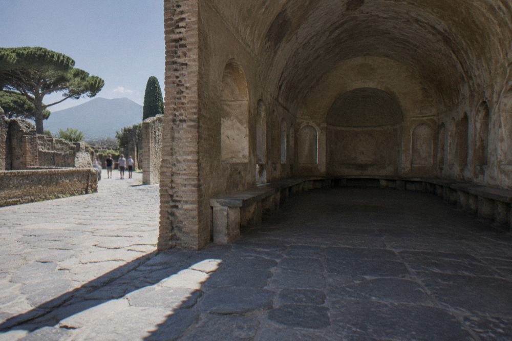 Narrow ancient alley in Pompeii lined with stone walls and doorways