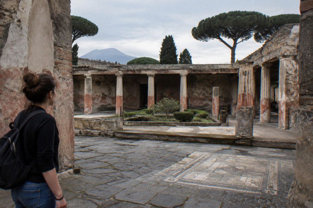 Guided group of visitors walking along a wide ancient street inside Pompeii