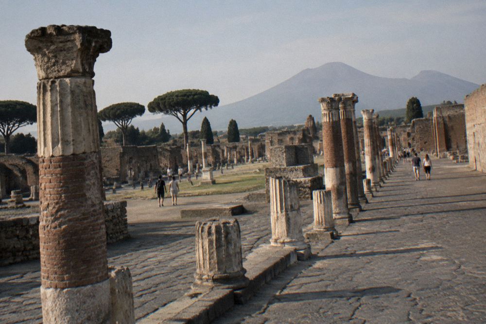 Crowd of visitors walking along a wide ancient street in Pompeii