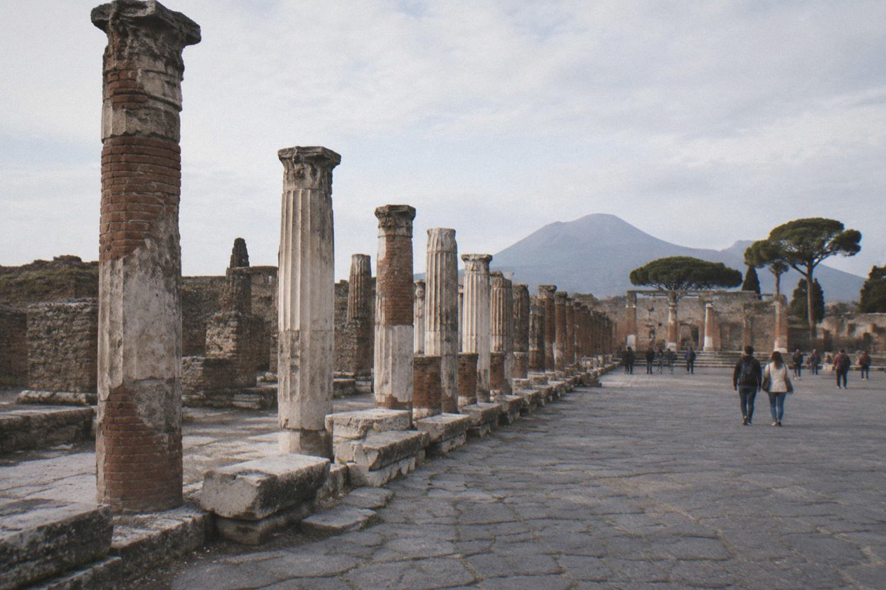 The stone street and ruts of Pompeii under low evening light with Vesuvius on the horizon
