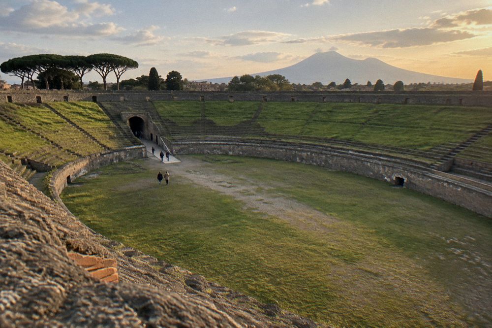 Visitors with small backpacks passing through a gate into the excavations