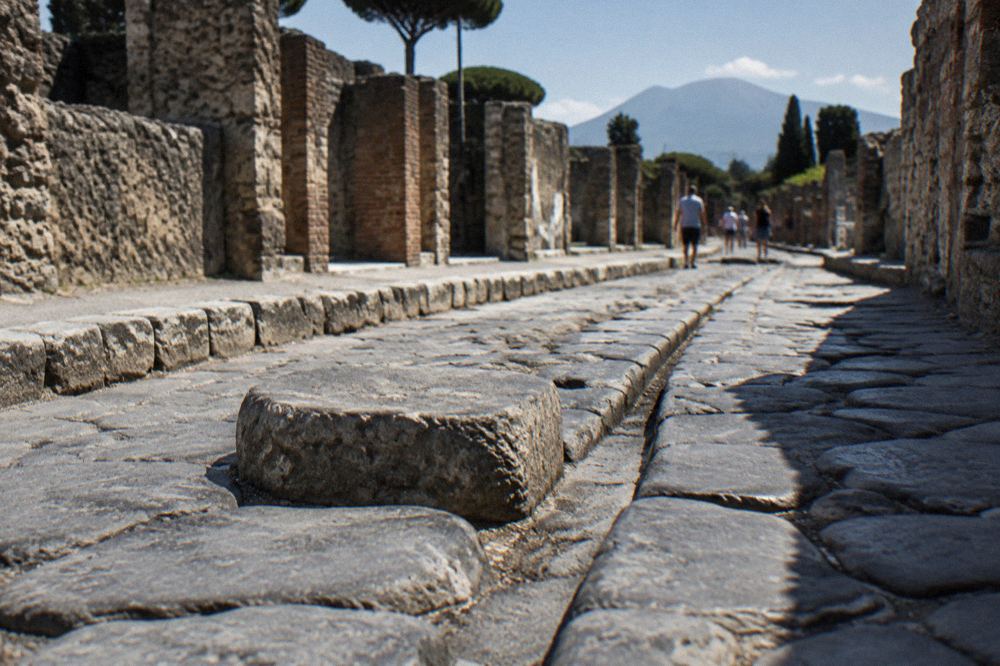 Visitors queuing at a stone gate entrance of Pompeii in warm afternoon light