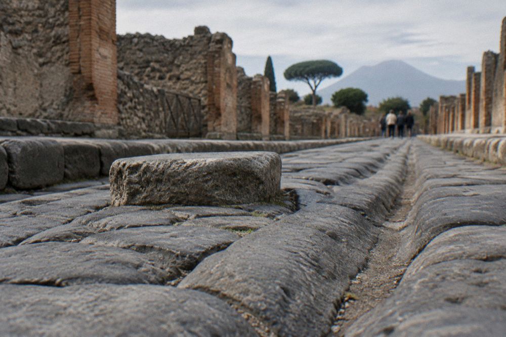 Small group of visitors listening to a guide beside an ancient stone wall in Pompeii