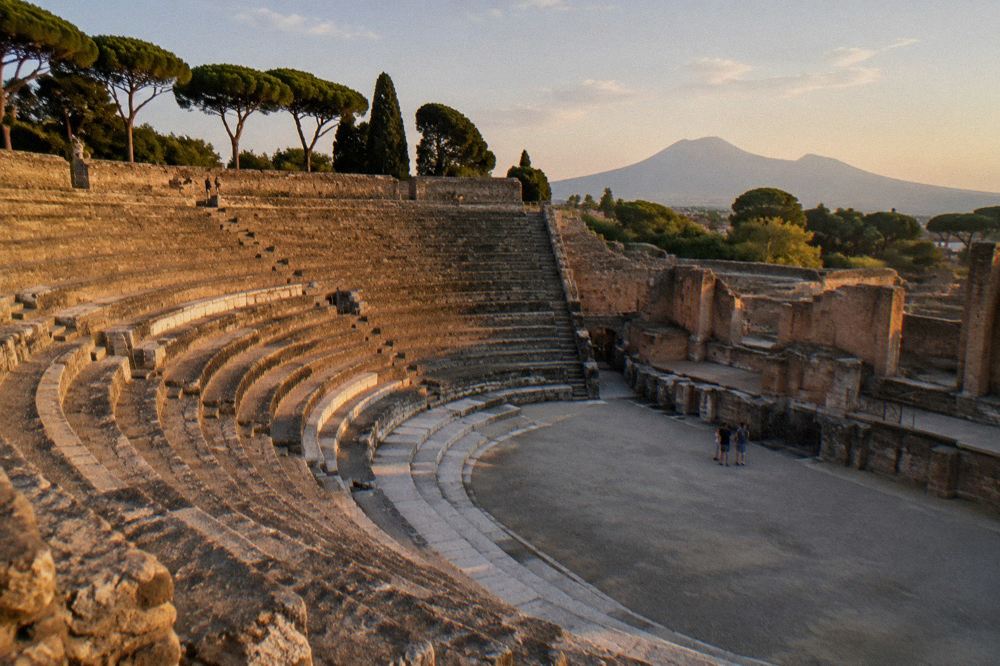 A tour coach parked near the entrance to Pompeii with the ruins and Mount Vesuvius in the background