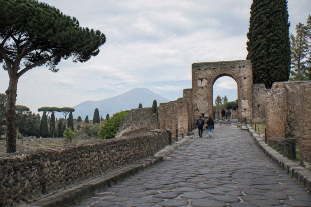 Ancient stone street in Pompeii with worn stepping stones and ruined brick walls under a clear sky