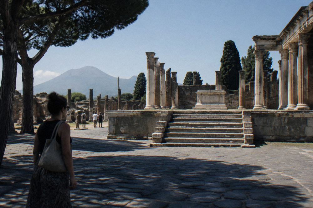Roman forum columns of Pompeii under a clear sky with few visitors on the stone paving