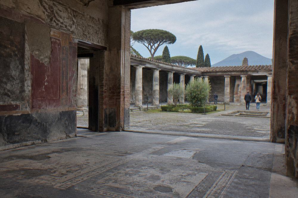 Ancient stone gateway at an entrance to Pompeii with the ruins visible beyond