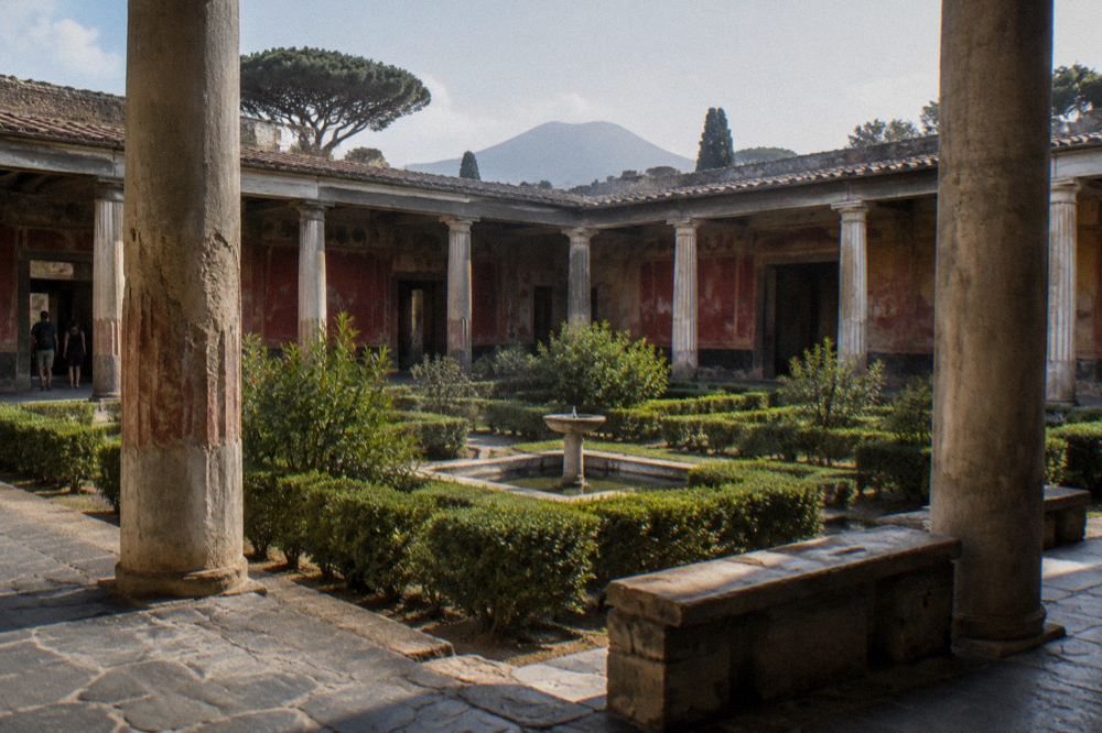 Small group of visitors listening to a guide beside excavated Roman walls in Pompeii