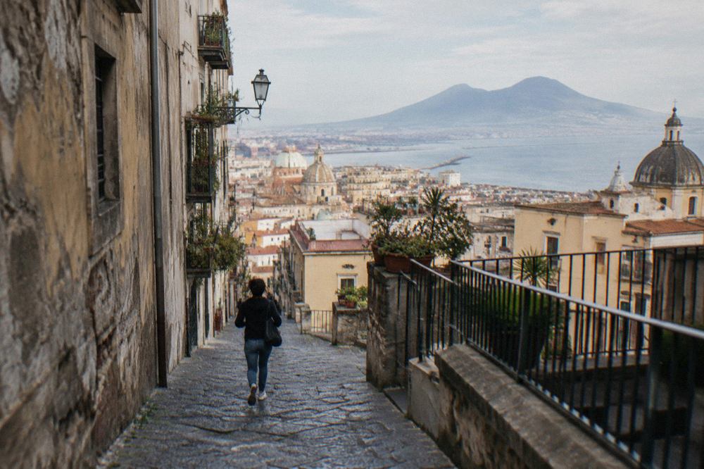 The stone-paved Street of Abundance in Pompeii with Mount Vesuvius rising in the distance
