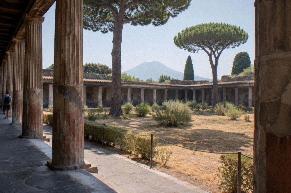 Long colonnaded street of ancient columns receding towards an arch under bright midday light