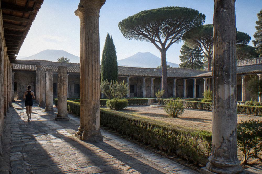 Stone-paved Roman street with ancient walls and Mount Vesuvius on the horizon