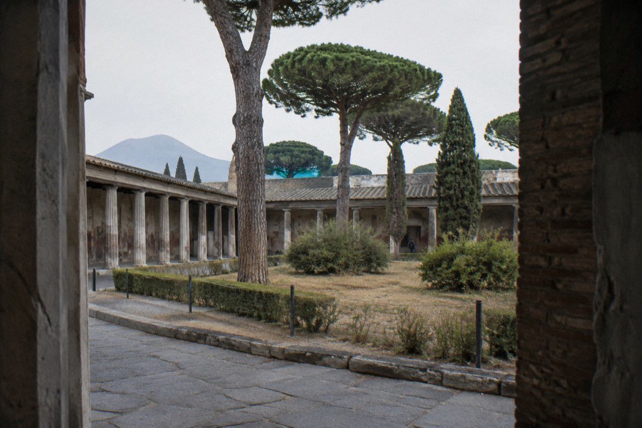 Stone-paved Roman street with ancient walls and Mount Vesuvius on the horizon