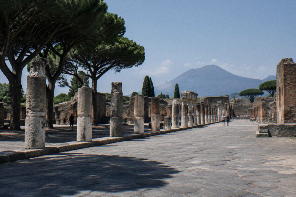 Deep shadows across a narrow paved lane in Pompeii at midday with bright white sunlight on old walls