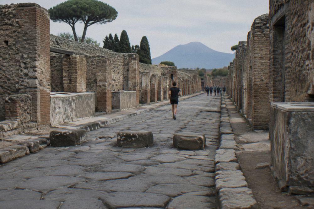 Rain clouds gathering over the excavated forum of Pompeii with dark stone and distant hills