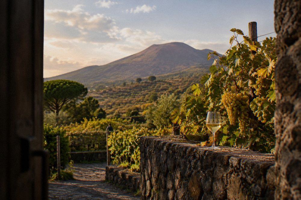 Glasses of red wine lined up on a wooden table overlooking the volcano