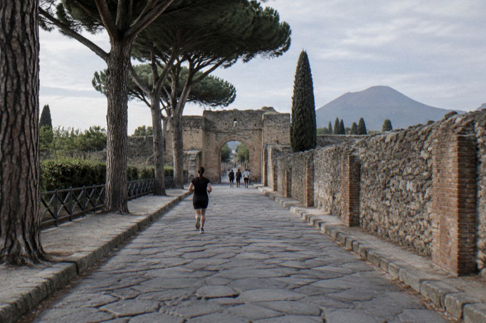 Excavated Roman street with worn stone wheel ruts under strong summer sunlight