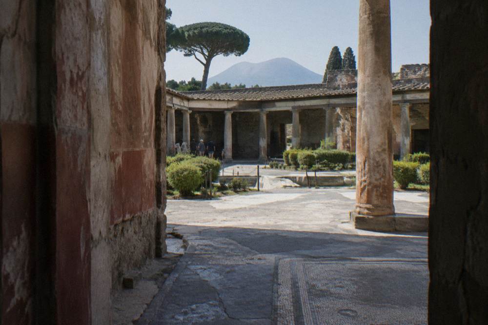 Wide view over the excavated rooftops and streets of Pompeii toward Mount Vesuvius