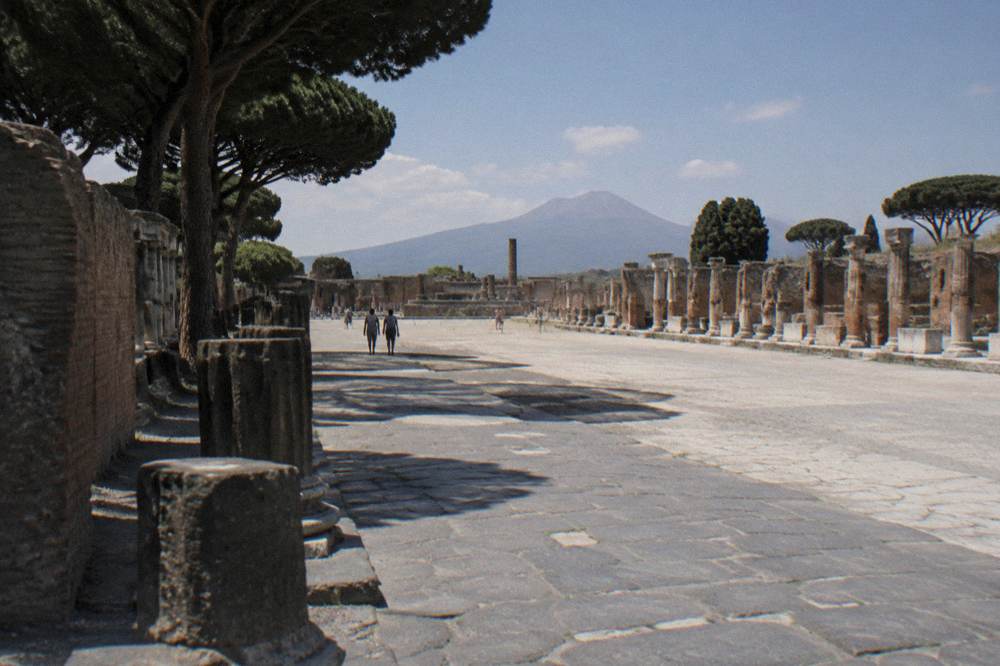 Stone-paved ancient street with cart ruts running between ruined walls in Pompeii