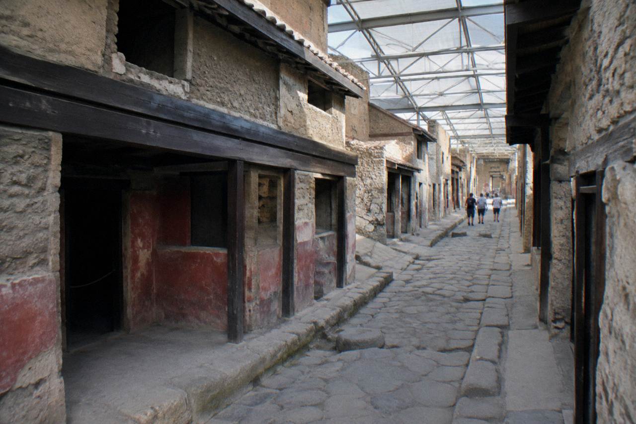 Stone-paved Roman street with wheel-worn ruts and ruined walls under a clear sky