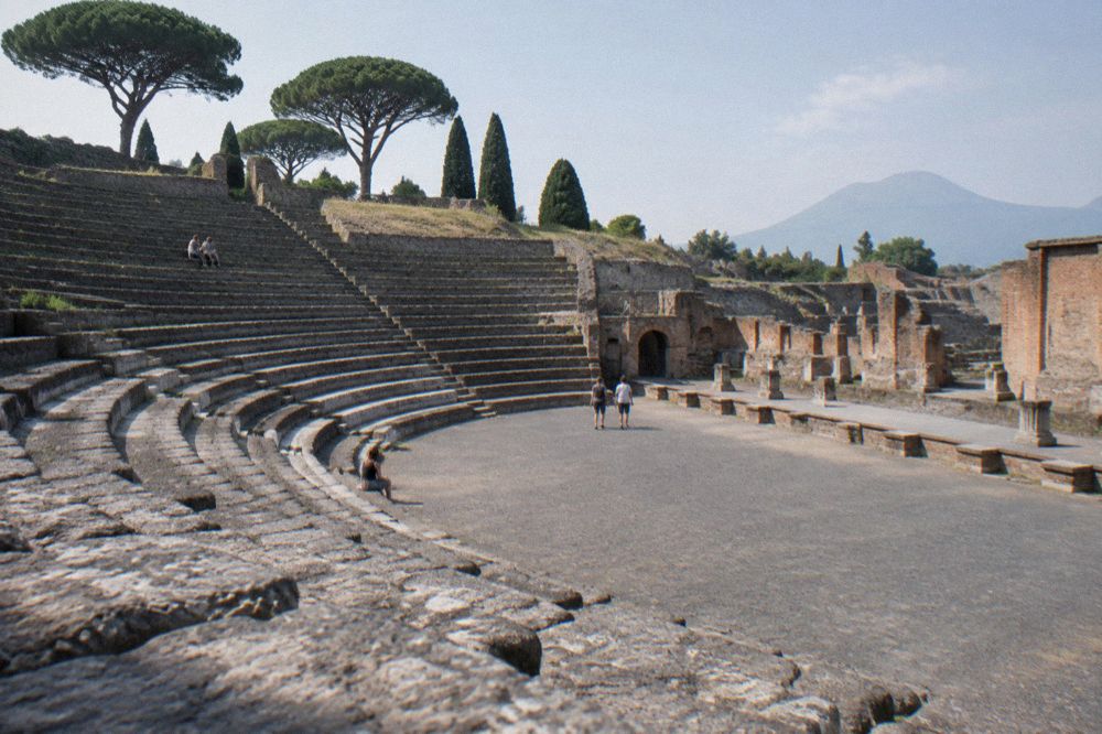 Guide and small group of visitors standing among the ruined walls of Pompeii