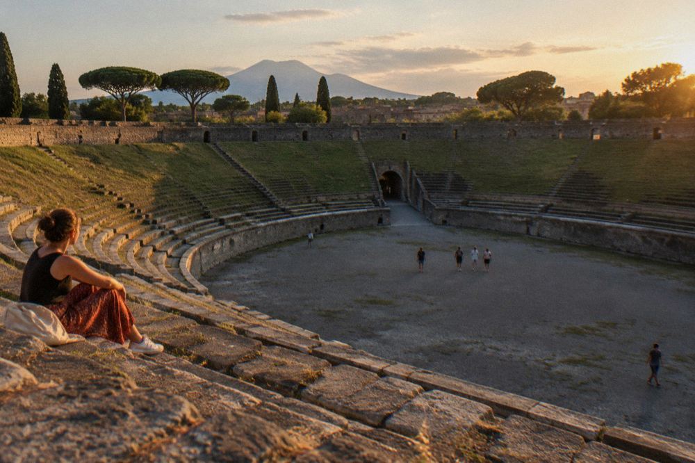 Sun setting over the excavated rooftops and walls of Pompeii with the modern town beyond