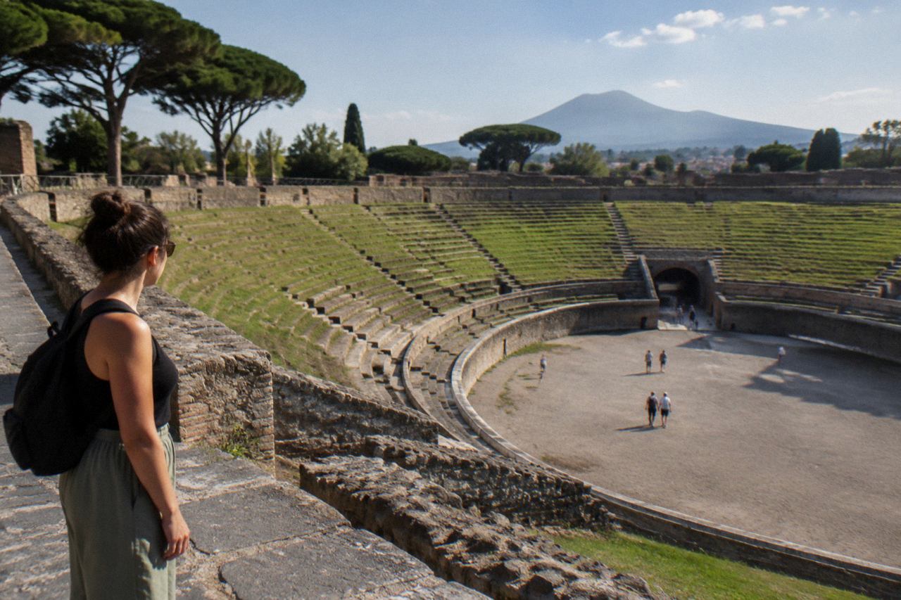 Ancient stone-paved street in Pompeii with worn wheel ruts and low ruined walls under a bright sky