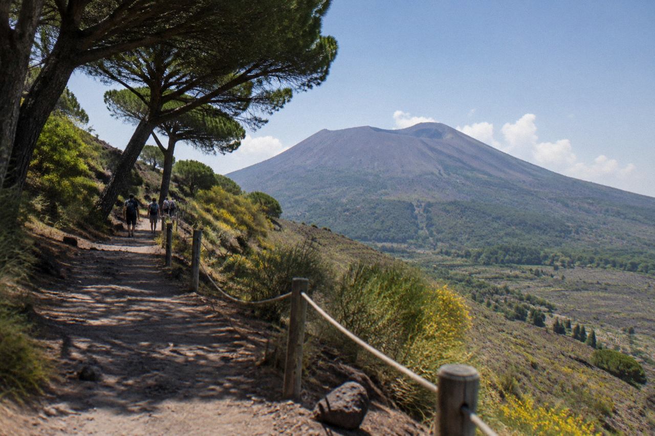 Ancient stone street in Pompeii with Mount Vesuvius rising in the background under a clear sky