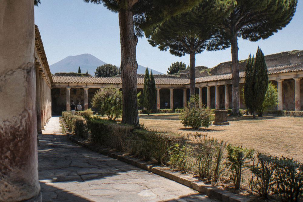 Visitors walking a stone-paved Roman street past ancient walls